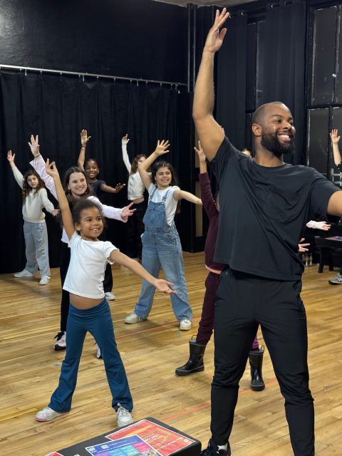A teaching artist leads students in a song & dance - Musical Theater Teaching Artists