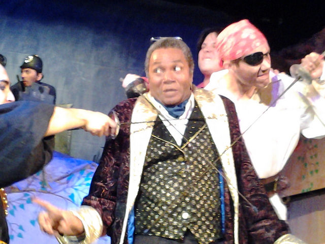 A General Surrounded: Darryl Maximilian Robinson as Major-General Stanley submits to buccaneers in the 2014 revival of The Pirates of Penzance at The San Pedro Theatre Club in LA.