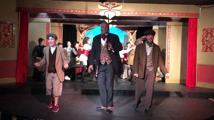Going 'Off To The Races'!: Joined on his left by Nate Becker as The Deputy and Master Nick Cricker II, and on his right by Eric S. Prahl as Durdles and Mr. Nick Cricker, Sr., Darryl Maximilian Robinson ( center ) in his dual roles of The Chairman Mr. William Cartwright and Mayor Thomas Sapsea leads the cast in the first act finale of the 2018 Saint Sebastian Players of Chicago revival of Rupert Holmes' Tony Award-winning Best Musical Whodunit 'The Mystery of Edwin Drood'. Photo courtesy of Afanofthemysteree.
