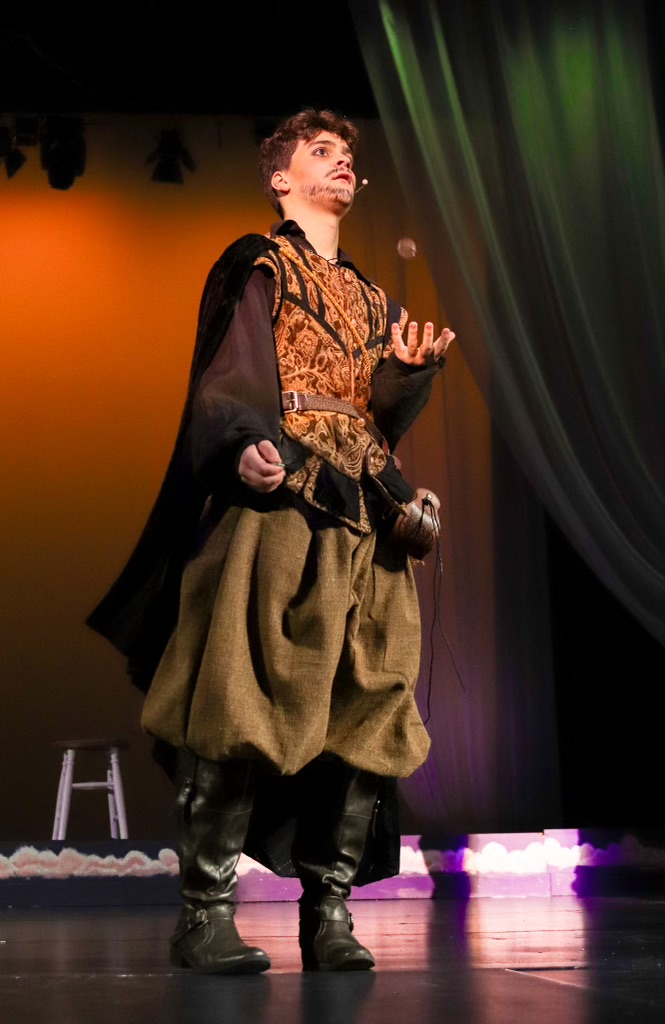 Guildenstern (Xavier Lago) flips a coin.