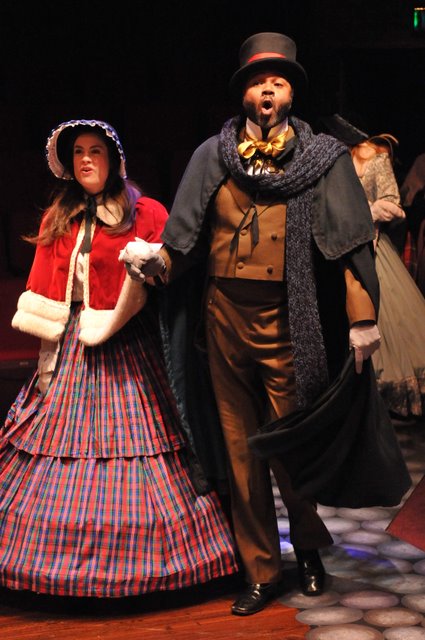 Caroling Spirits: Kate Ponzio as A Caroler ( who becomes The Ghost of Christmas Past ) and Darryl Maximilian Robinson as A Caroler ( who beomes The Ghost of Christmas Present ) in A Christmas Carol.
