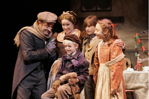 Bob Cratchit (Daniel Blinkoff, left) with his wife (Jennifer Parsons) and his childre Photo