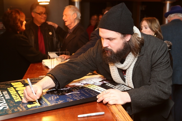 Cast member David Haverty signs a poster during the world premier of 