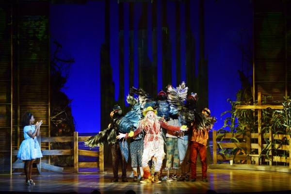 Dorothy (Destinee Rea), left, watches as the Scarecrow (David LaMarr, center) sings a Photo