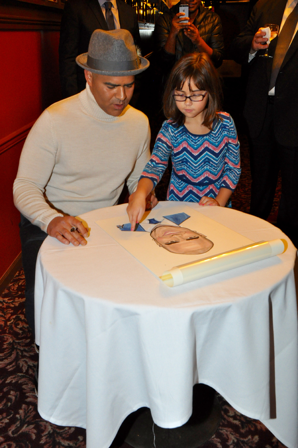 Daughter Jadelyn picks out spot for Christopher Jackson to sign his caricature  Photo