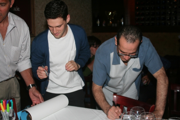 Justin Bartha and Tony Shalhoub signing print copies of the portrait to be auctioned  Photo